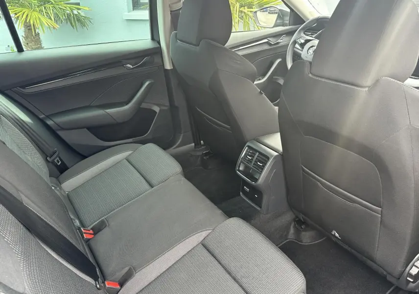 Vue intérieure arrière de la Skoda Octavia Combi gris graphite, montrant les sièges arrière et la console centrale avec aérateurs.