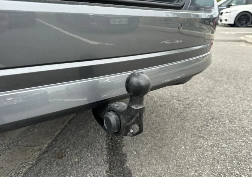 Gros plan sur le crochet d'attelage pivotant noir sous le pare-chocs arrière gris graphite d'une Skoda Octavia Combi 2024.