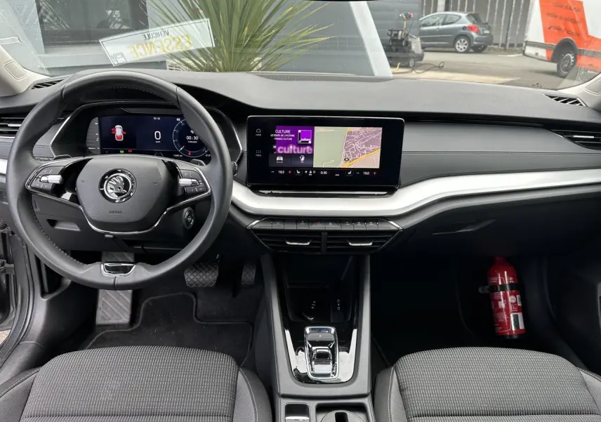 Intérieur de la Skoda Octavia Combi 2024 vu de face, tableau de bord noir avec écran tactile et volant multifonctions.