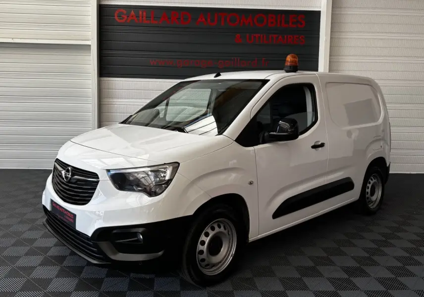 Opel Combo blanc en 3/4 avant droit avec gyrophare orange sur le toit et jantes acier simples.