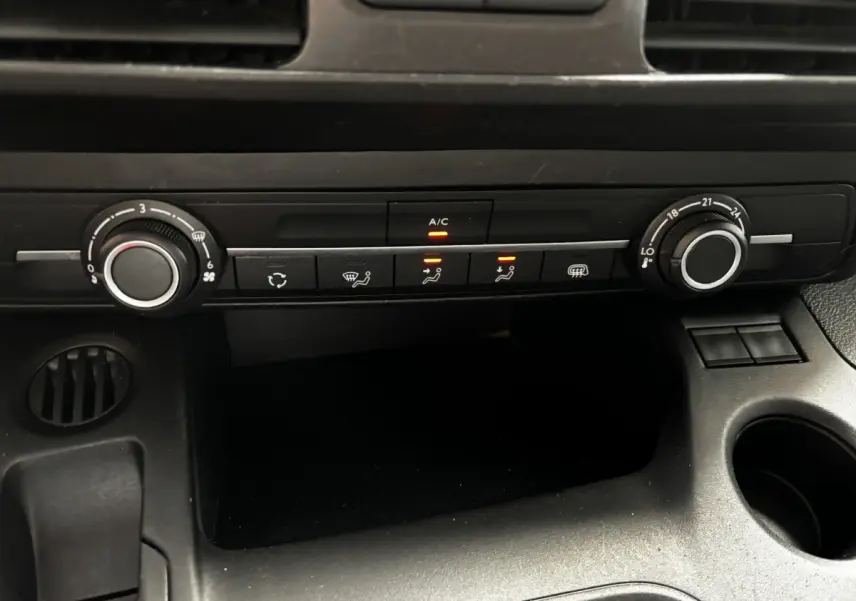 Gros plan sur la console centrale noire de l'Opel Combo 2021 montrant les commandes de climatisation avec voyants allumés.