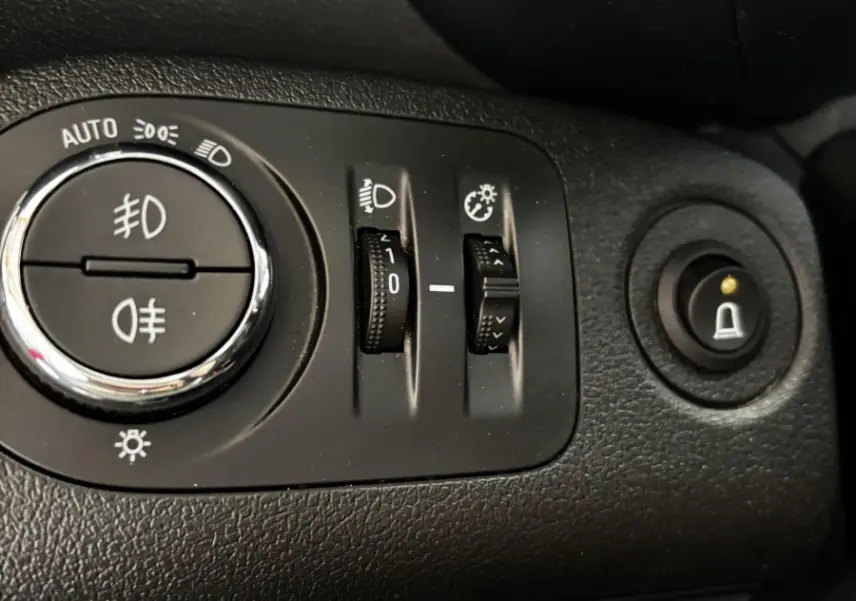Gros plan sur les commandes d'éclairage et réglages du tableau de bord noir de l'Opel Combo blanc 2021.