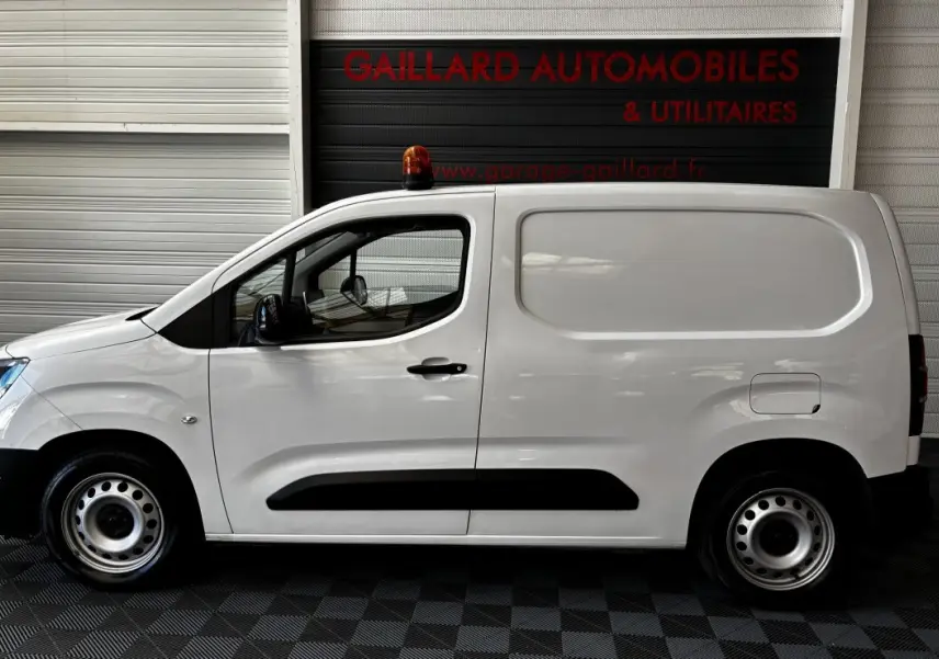 Profil côté gauche d'un utilitaire blanc Opel Combo 1.5 diesel 100ch avec gyrophare orange sur le toit.