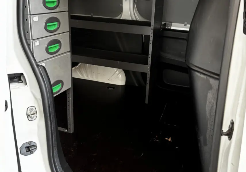 Vue intérieure de la zone de chargement du fourgon blanc Opel Combo 2021 avec étagères métalliques et cloison pleine noire.