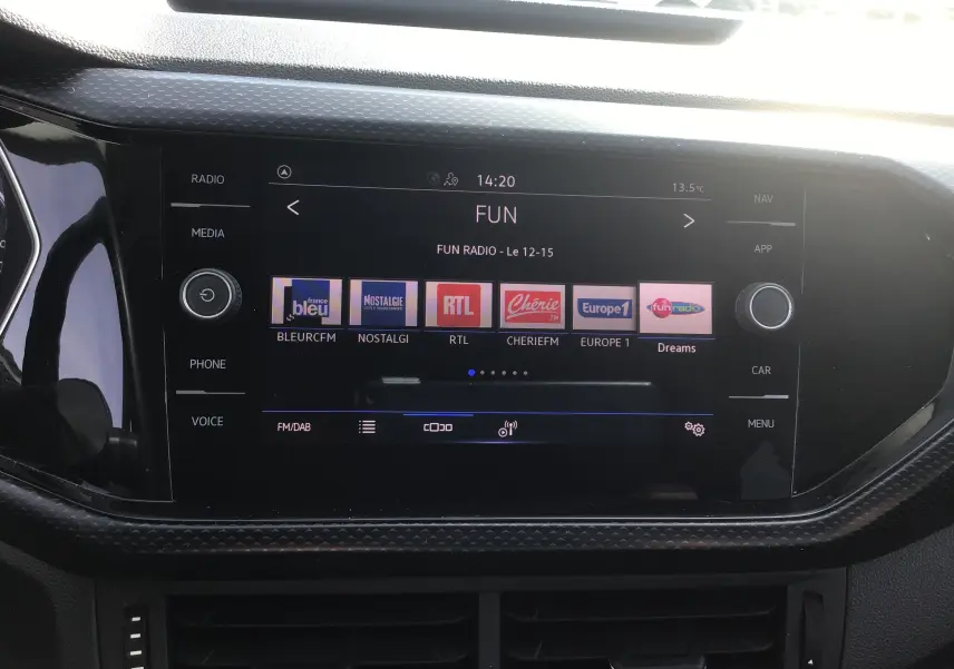 Écran tactile central du Volkswagen T-Cross blanc 2021 affichant les stations radio FM avec interface moderne.