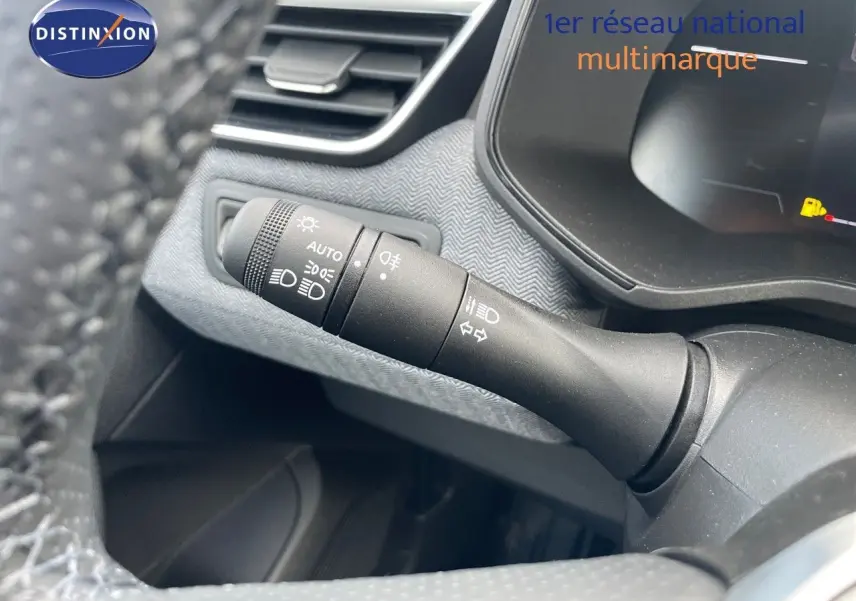 Gros plan sur la commande des phares à gauche du volant d'une Renault Clio bleu Iron Metal 2025, intérieur moderne.