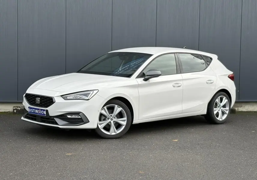 Vue 3/4 avant droite d'une SEAT Leon 1.5 e-TSI 150 DSG7 FR blanche avec jantes alliage 17 pouces et vitres surteintées.