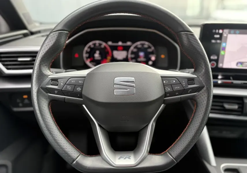 Vue rapprochée du volant cuir perforé noir avec logo FR de la SEAT LEON 1.5 e-TSI 150 DSG7 2024.