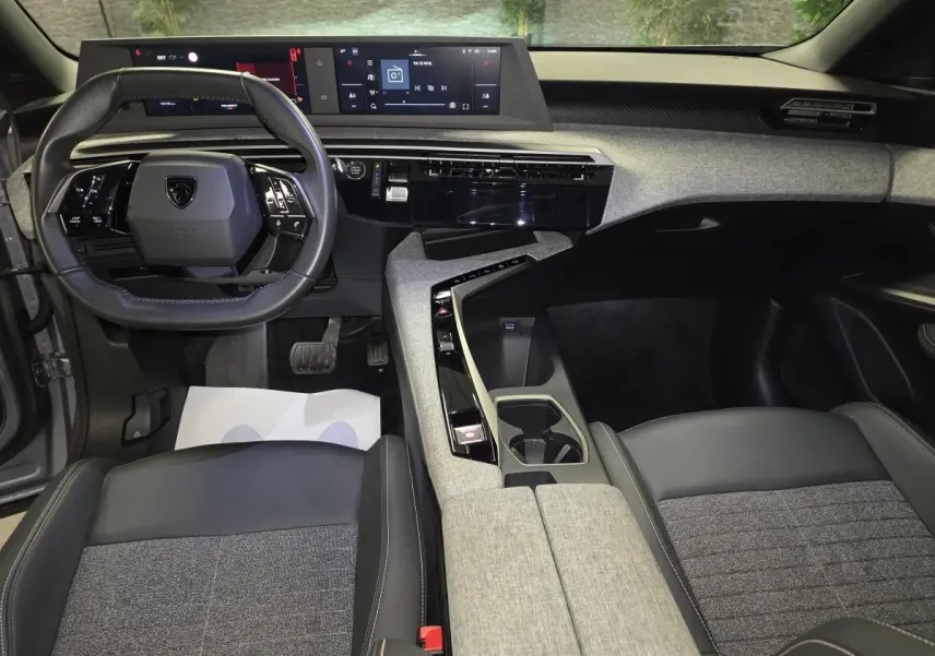 Vue intérieure avant du Peugeot 3008 gris 2025, mettant en valeur le tableau de bord numérique et la console centrale avec décor tissu Rimini.