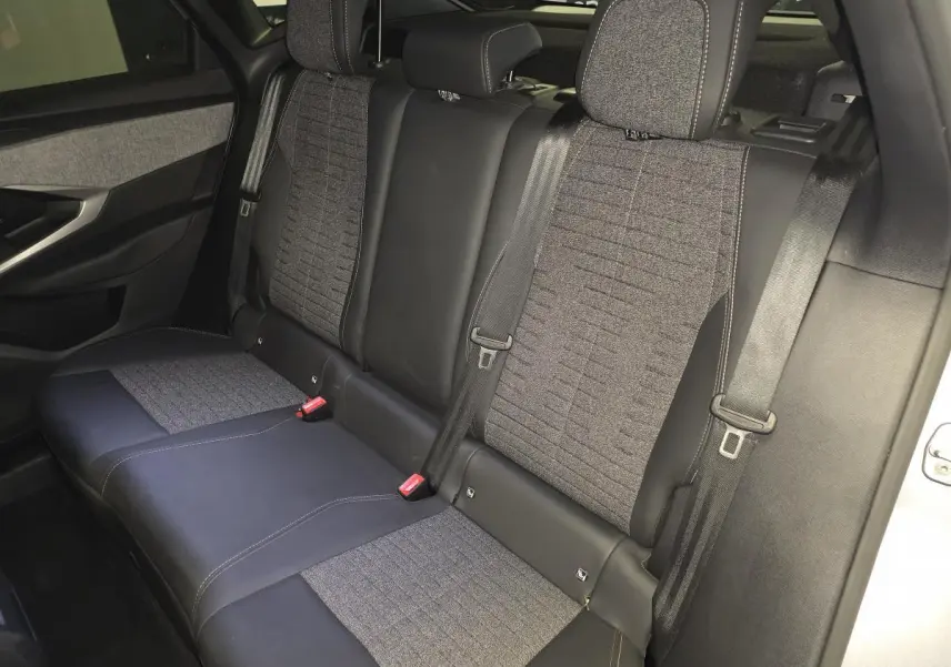 Vue intérieure de la banquette arrière du Peugeot 3008 hybride 2025, avec sellerie tissu gris et cuir noir.