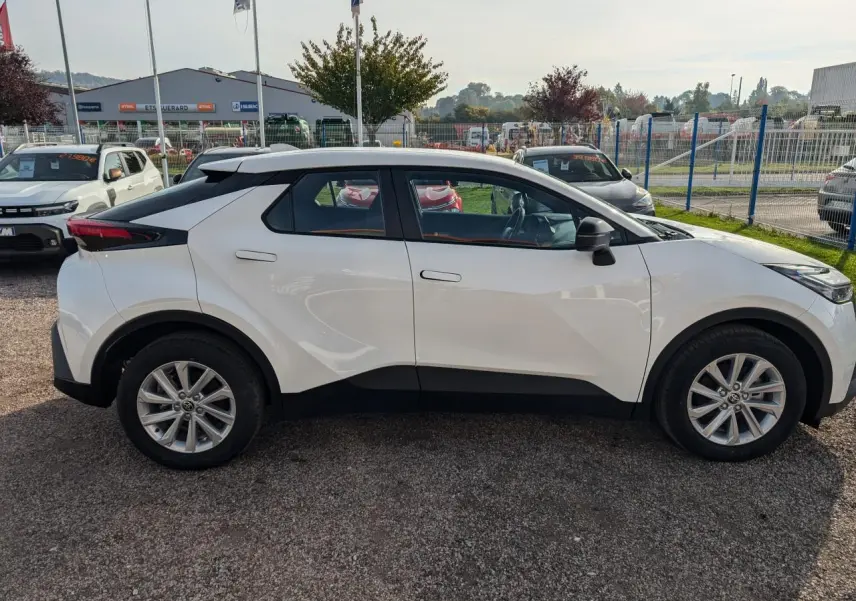 Profil côté gauche du Toyota C-HR 2024 blanc, avec jantes alliage 17 pouces et poignées affleurantes.