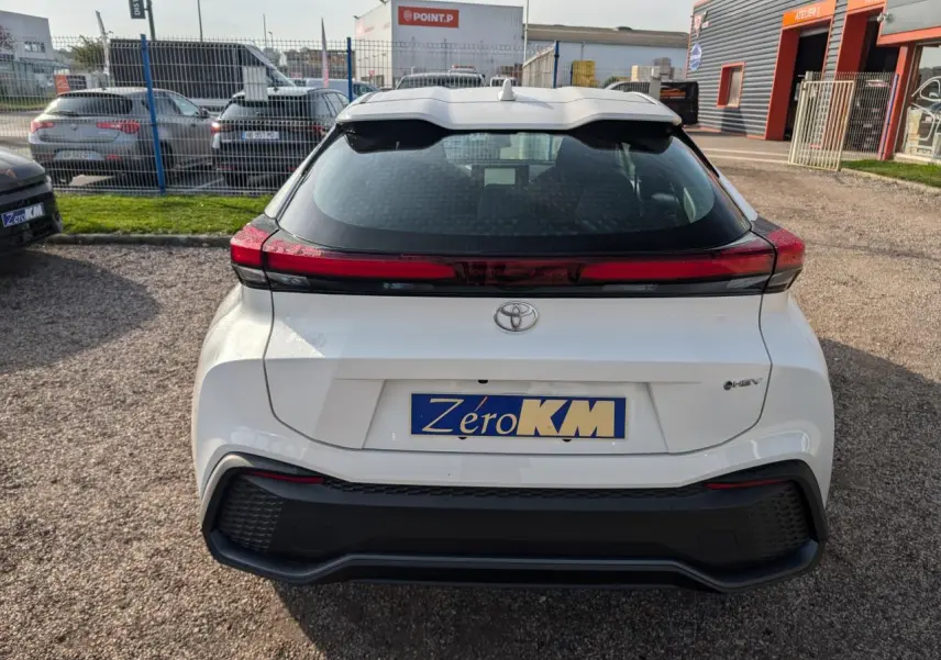 Vue arrière d'un Toyota C-HR blanc 2024 avec feux arrière full LED et plaque d'immatriculation "Zéro KM" visible.