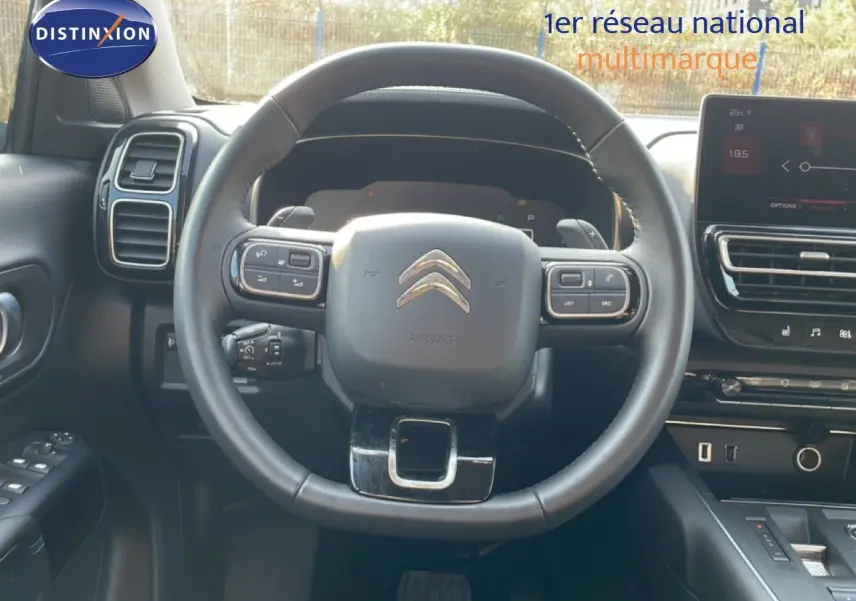 Vue intérieure centrée sur le volant du Citroën C5 Aircross 2025, avec tableau de bord et écran tactile visibles.