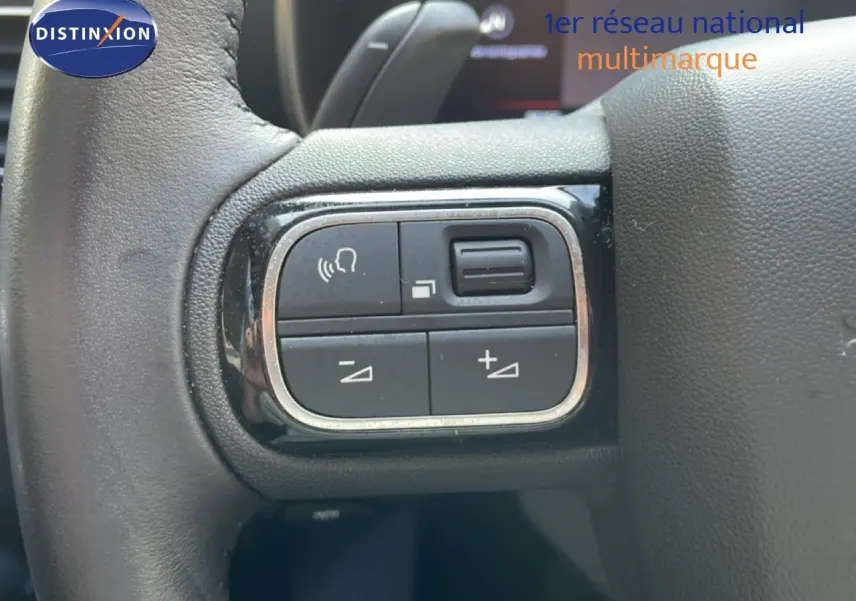 Gros plan sur les commandes de volume et de voix au volant du Citroën C5 Aircross 2025, intérieur noir.