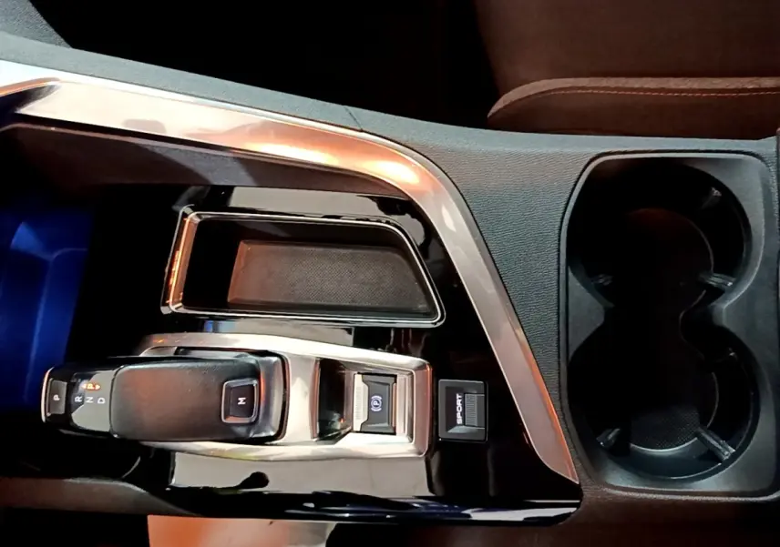 Gros plan sur la console centrale noire brillante du Peugeot 5008 gris clair, avec levier de vitesse automatique et bouton Sport.