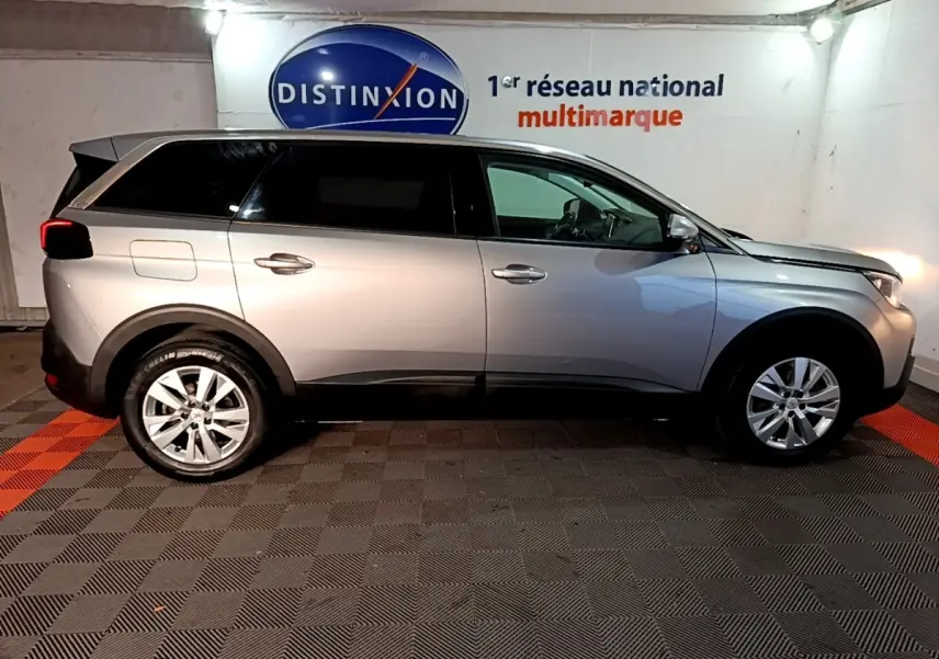 Vue latérale droite d'un Peugeot 5008 gris clair 2020 stationné en intérieur, avec jantes alliage et vitres teintées.