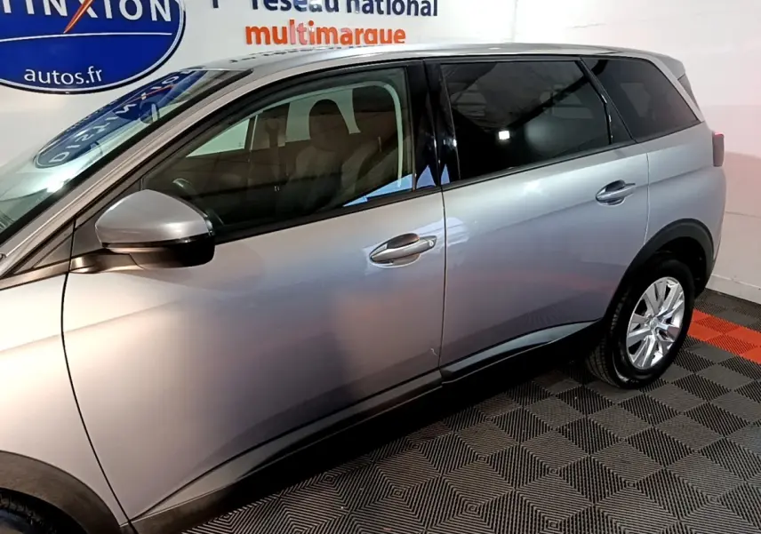 Vue latérale côté gauche d’un Peugeot 5008 gris clair, mettant en valeur ses portes et rétroviseur extérieur.