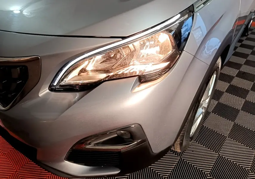 Gros plan sur l'avant droit gris clair du Peugeot 5008 2020, mettant en valeur le phare allumé et la calandre.
