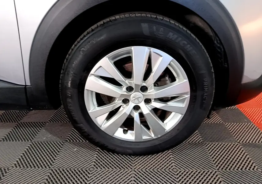 Gros plan sur la roue avant droite avec jante alliage argentée du Peugeot 5008 gris clair, détail du pneu Michelin.