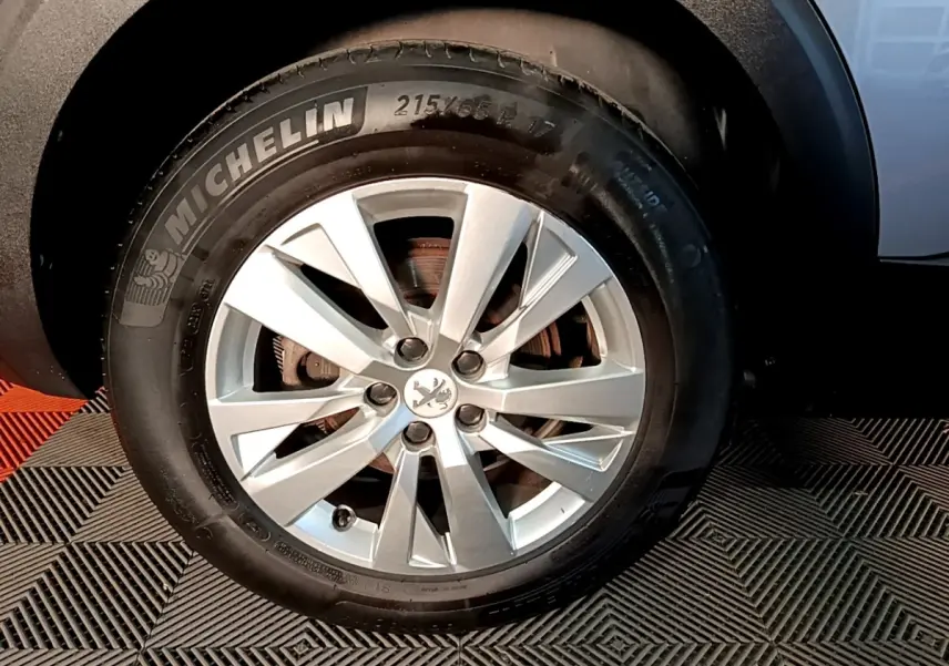 Gros plan sur la roue avant droite du Peugeot 5008 gris clair, avec jante alliage et pneu Michelin visible.