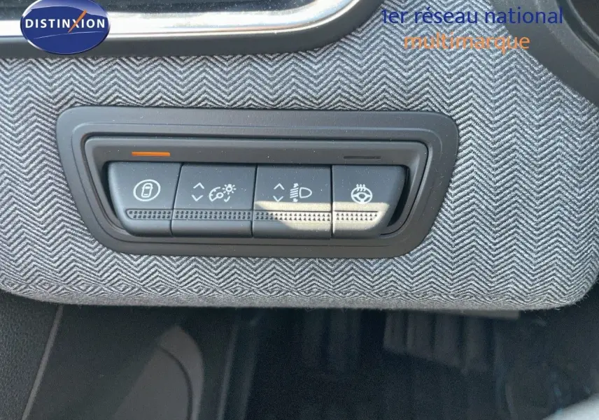 Gros plan sur les commandes d'éclairage intégrées dans le tableau de bord en tissu gris de la Renault Clio TCe 90ch Techno.