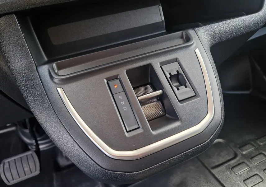 Gros plan sur la commande de boîte automatique et prise 12V du Citroën Jumpy XL gris titane, intérieur noir.