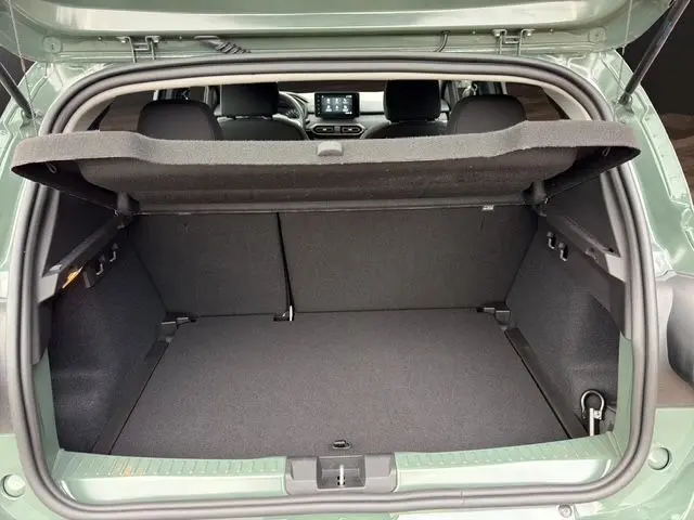 Vue arrière du coffre ouvert de la Dacia Sandero Stepway 2025 en kaki lichen, montrant un espace de rangement spacieux et la tablette arrière.