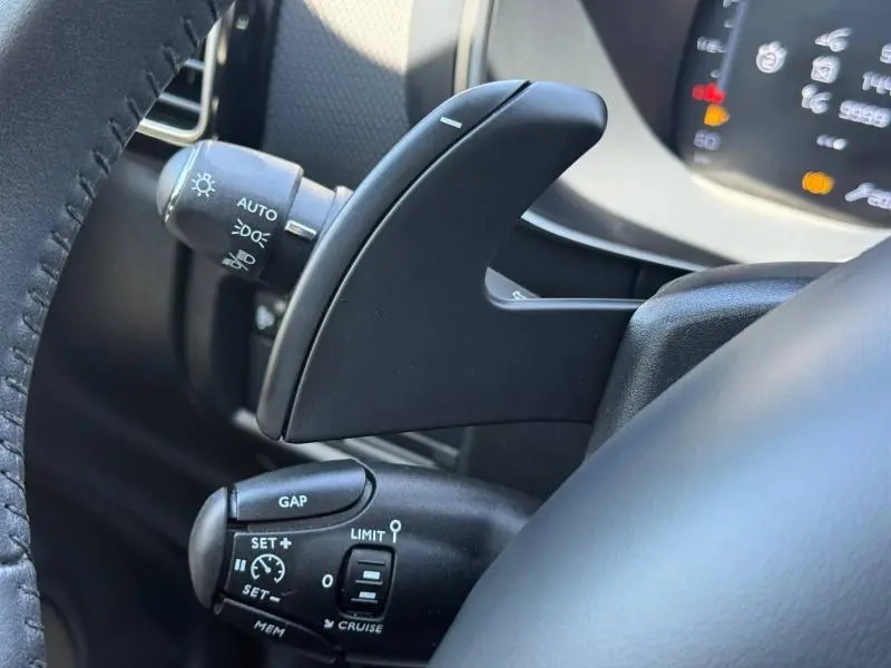 Gros plan sur les commandes au volant noir du Citroën C5 Aircross gris acier, avec palettes de boîte automatique visibles.