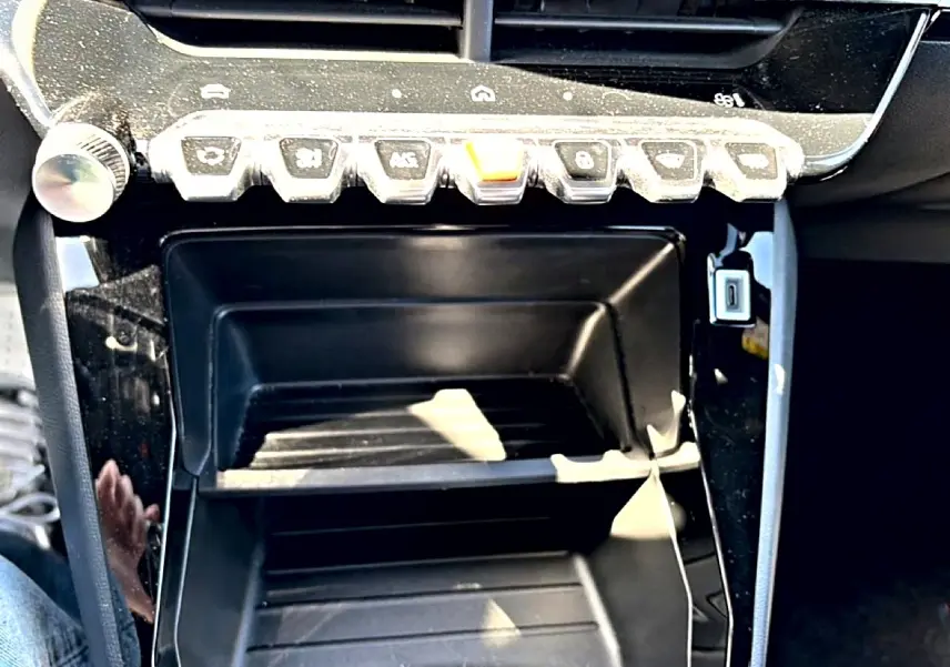 Gros plan sur la console centrale noire du Peugeot 2008 1.2 100 style avec rangements et boutons de commande.