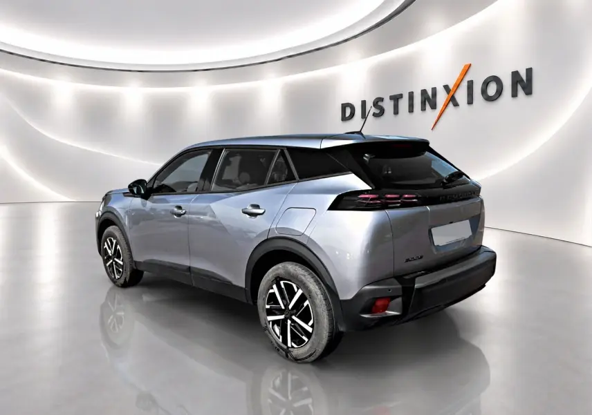 Peugeot 2008 gris en 3/4 arrière droit, avec toit noir et jantes bicolores dans un showroom lumineux.