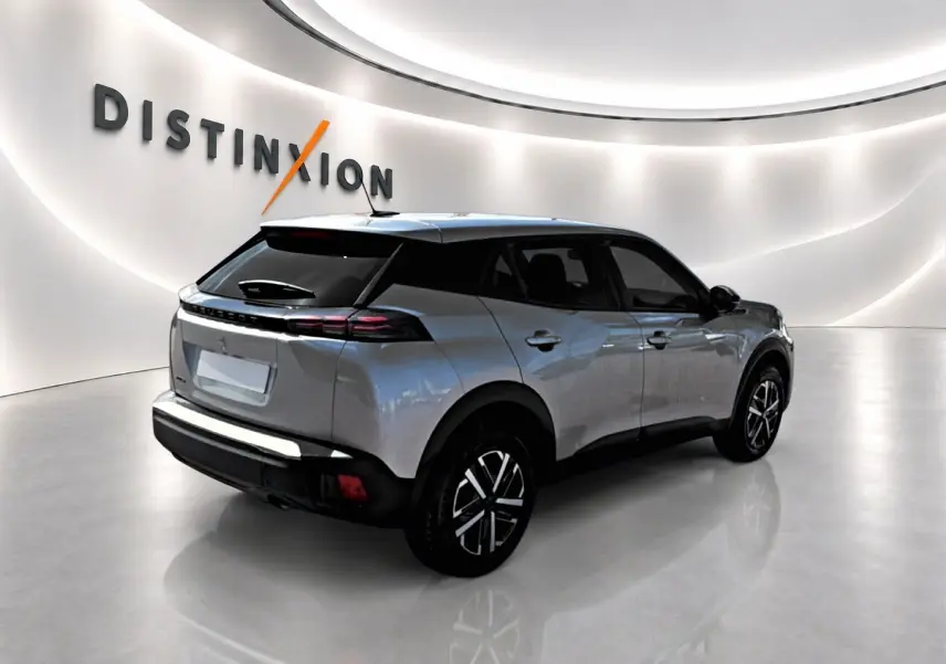 Peugeot 2008 gris en 3/4 arrière droit, avec toit noir et feux arrière LED distinctifs dans un showroom lumineux.