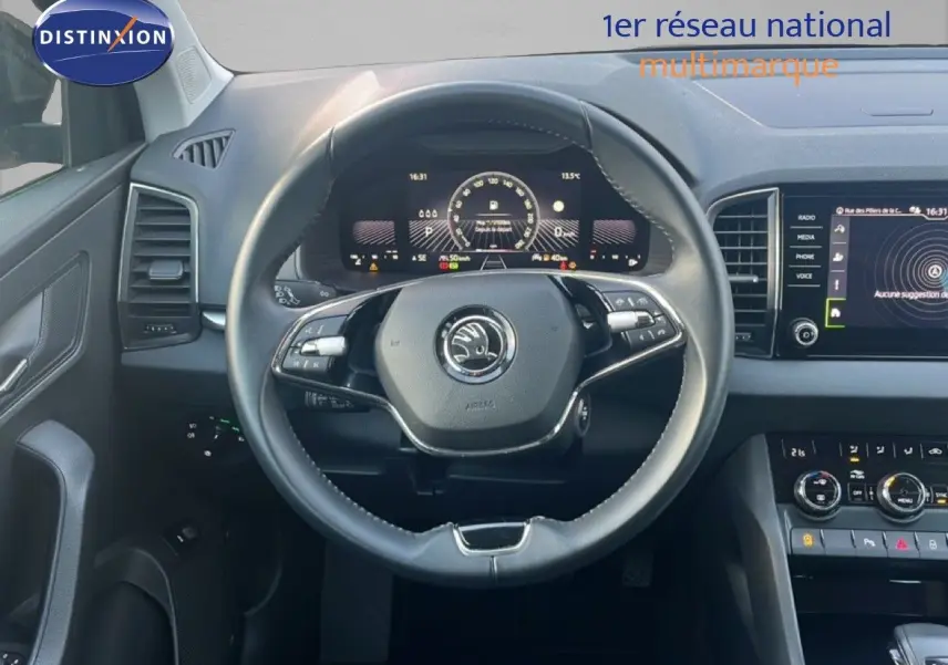 Vue intérieure centrée sur le volant et le tableau de bord numérique d'une Skoda Karoq noir Magic Metal 2023.