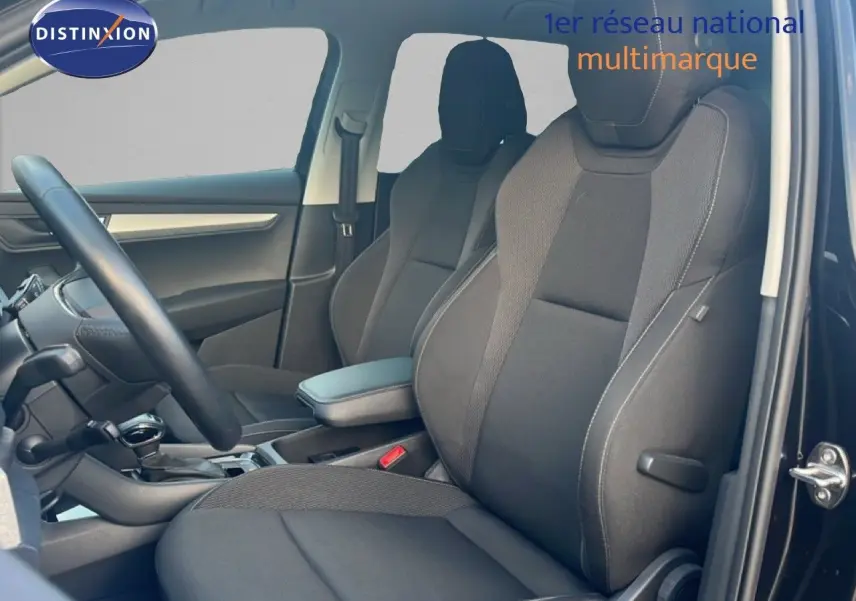 Intérieur côté conducteur d'un Skoda Karoq noir Magic Metal 2023, sièges tissu noir et tableau de bord moderne.