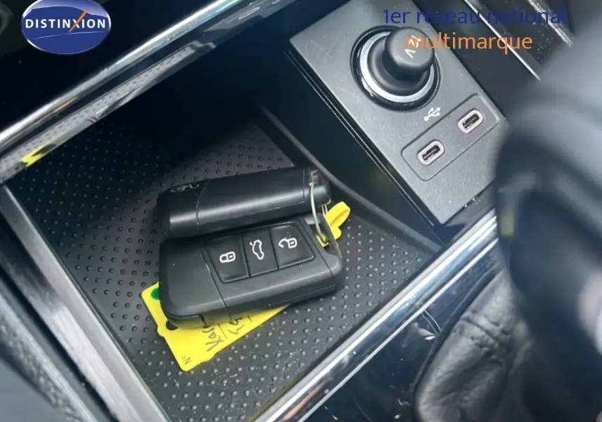 Gros plan sur la console centrale d'un Skoda Karoq noir avec clé de voiture et ports USB visibles.