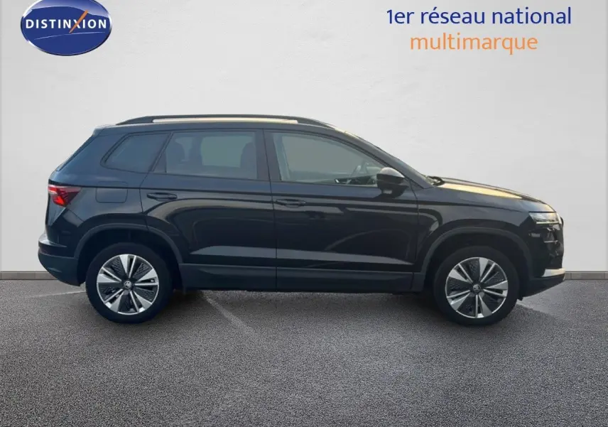 Profil côté gauche d'un SUV SKODA KAROQ noir Magic Metal 2023, avec jantes bi-ton et toit ouvrant visible.
