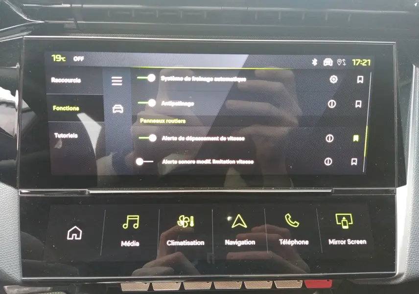 Écran tactile central de la Peugeot 408 Hybrid blanc, affichant les réglages des aides à la conduite et fonctions multimédia.