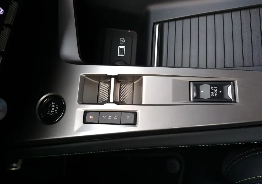 Vue rapprochée de la console centrale argentée du Peugeot 408 Hybrid 2024 avec boutons de boîte auto et mode de conduite.