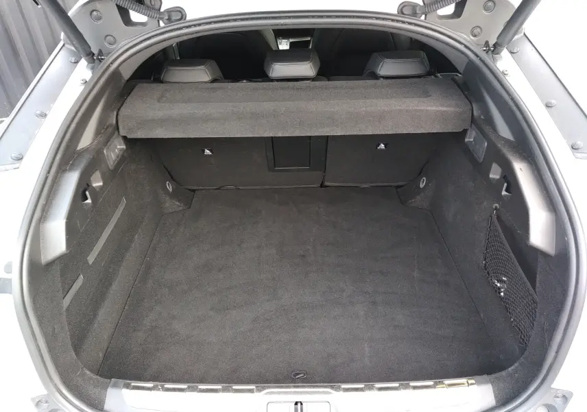 Vue plongeante sur le coffre spacieux et noir de la Peugeot 408 Hybrid 136ch GT blanc Okenite, banquette arrière visible.