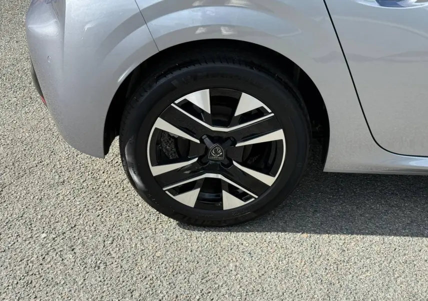 Gros plan sur la roue arrière gauche de la Peugeot 208 gris Artense avec jante alu bicolore au design moderne.