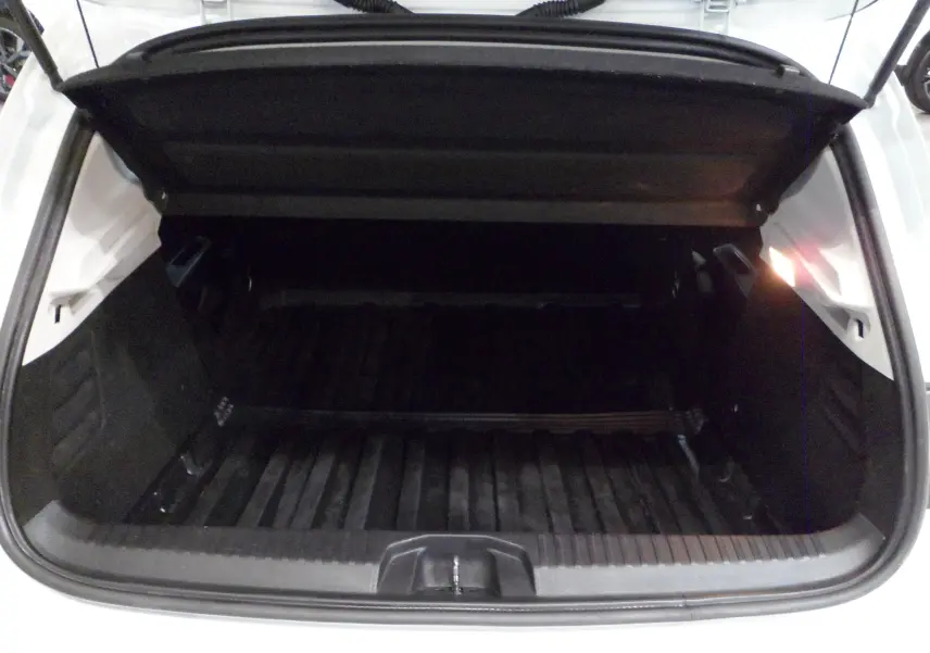 Coffre ouvert vu de l'arrière d'une Renault Clio V Blanc Glacier, montrant l'espace de chargement vide et la trappe de coffre.