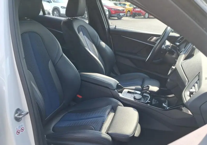 Vue intérieure côté conducteur d'une BMW Série 1 blanche 120i M Sport 2021 avec sièges sport cuir et alcantara.