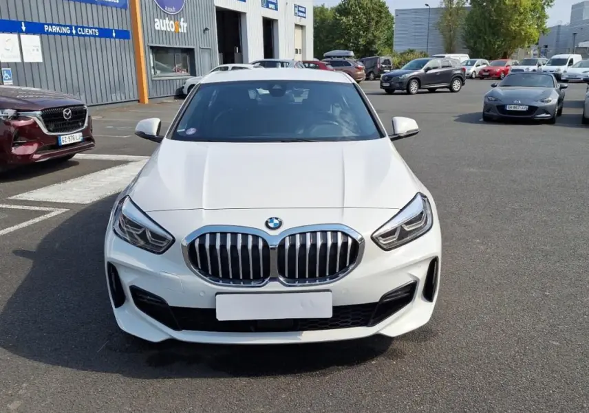 Vue frontale d'une BMW Série 1 blanche 120i M Sport avec calandre double haricot et phares LED marqués.