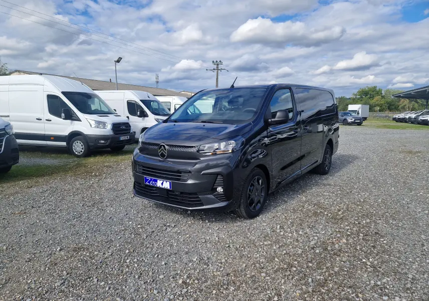 Citroën Jumpy Cabine Approfondie gris titane vu en 3/4 avant droit sur un parking extérieur avec plusieurs fourgons blancs.