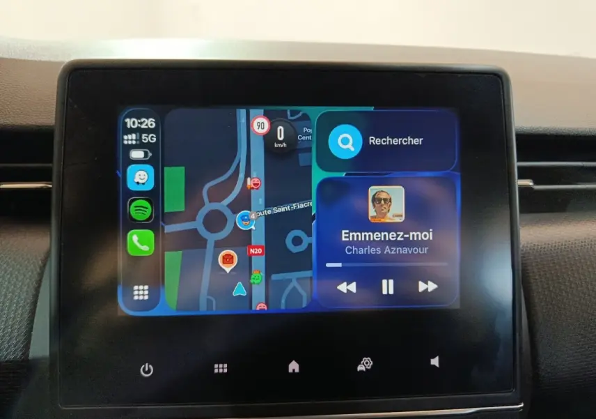 Écran tactile central de la Renault Clio gris clair 2023 affichant navigation et musique en cours.