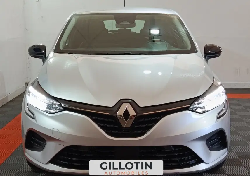 Vue frontale d'une Renault Clio Equilibre TCe 90 gris clair avec phares LED allumés en intérieur.