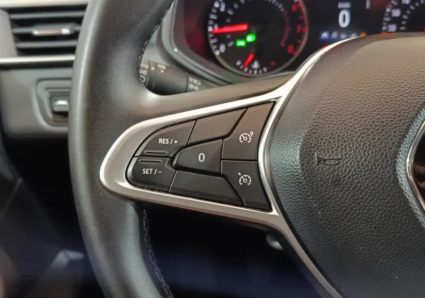 Gros plan sur le volant cuir noir de la Renault Clio 2023, avec commandes de régulateur de vitesse au côté gauche.