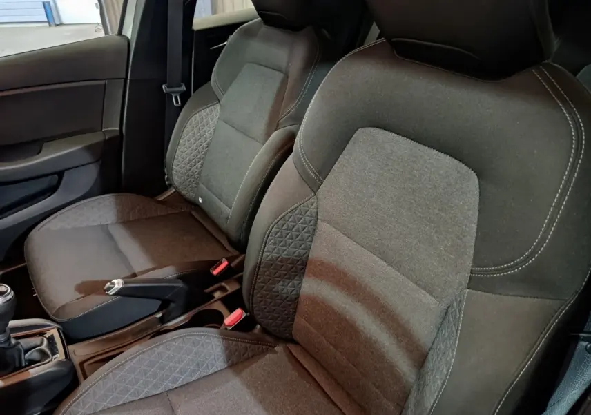 Gros plan sur les sièges avant gris foncé de la Renault Clio Equilibre TCe 90, avec coutures blanches apparentes.