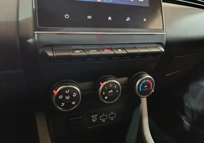 Vue rapprochée des commandes de climatisation et des ports USB sur le tableau de bord noir de la Renault Clio gris clair 2023.