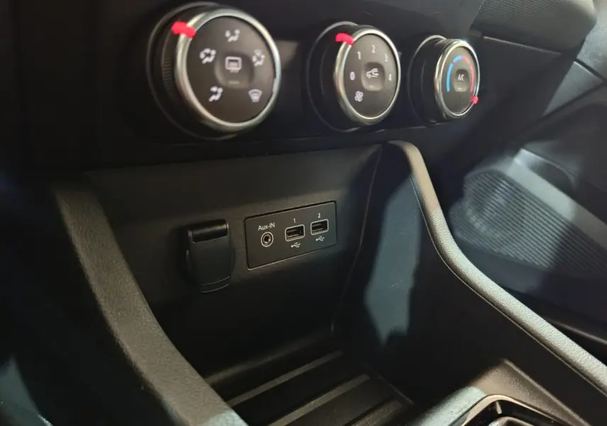 Gros plan sur les commandes de climatisation et les ports USB/Aux-in du tableau de bord noir de la Renault Clio 2023.