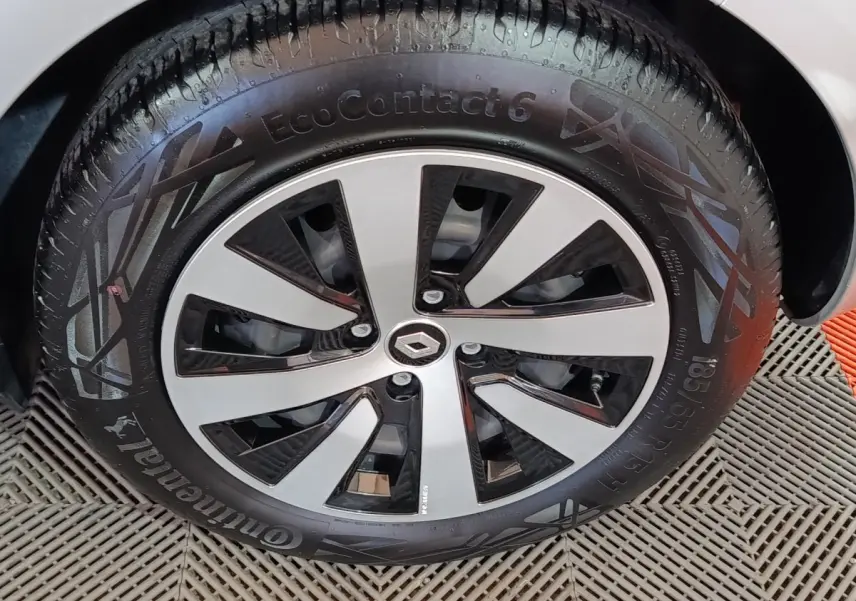 Gros plan sur la roue avant gauche de la Renault Clio gris clair, mettant en valeur la jante moderne bicolore et le pneu Continental.